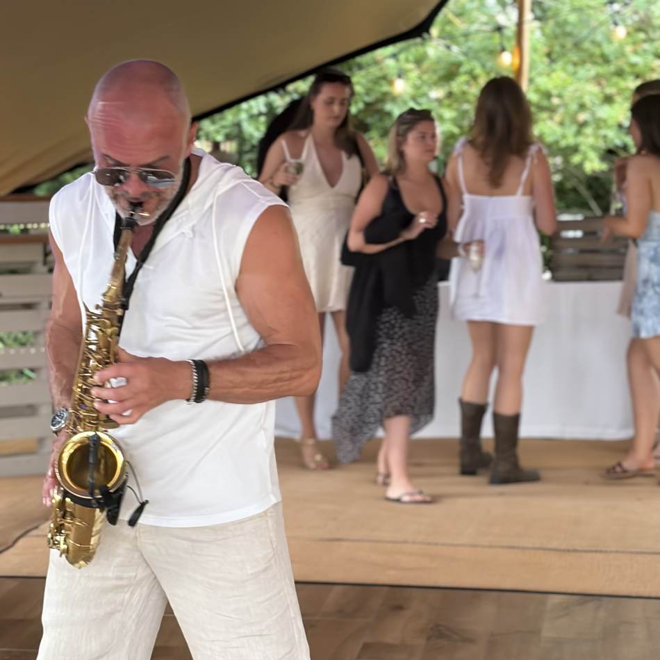Paul Martyn playing saxophone with guests dancing behind him