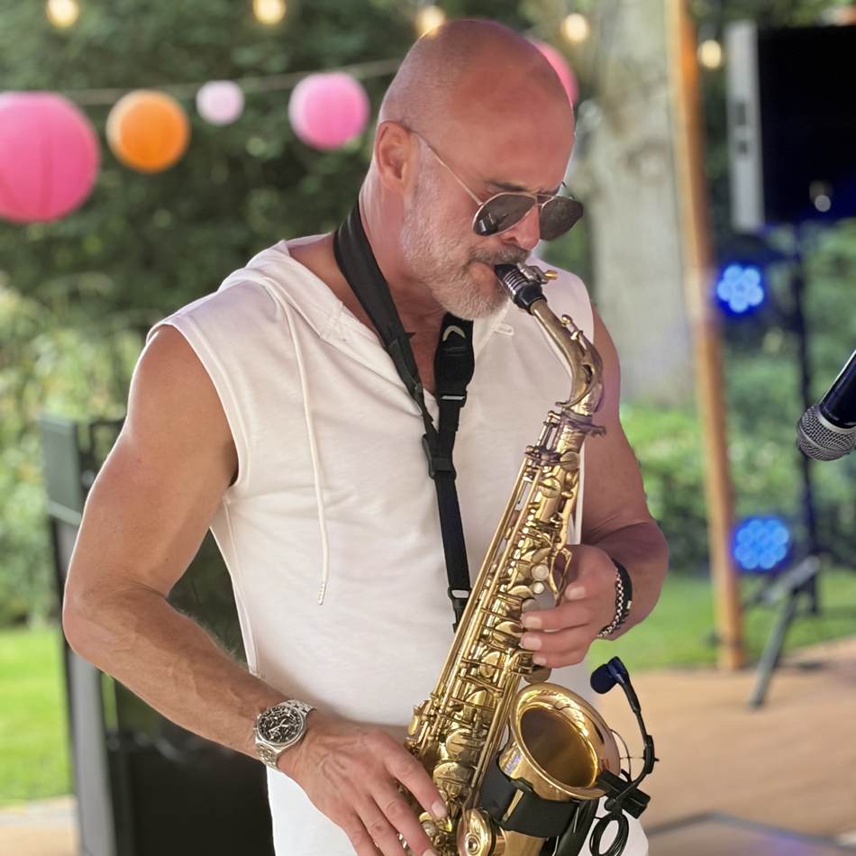 Paul Martyn playing saxophone under festoon lighting